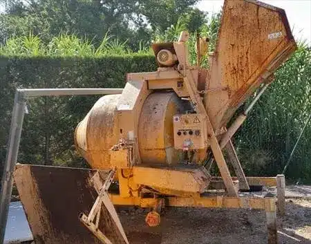 Large yellow industrial concrete mixer with a metal hopper and control panel outdoors.