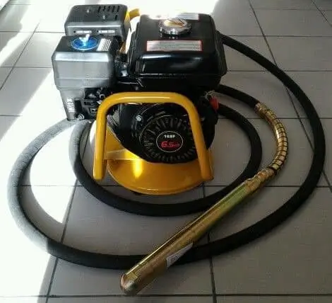 Portable gasoline engine with a long flexible hose and metal vibrating poker on a tiled floor.