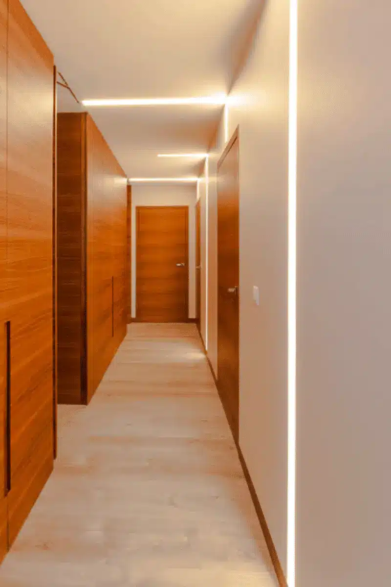 Sleek corridor featuring warm wood cabinetry and geometric LED light strips.